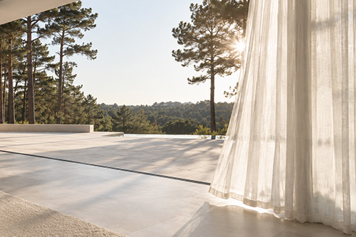 Light sheer curtains with soft movement framing large glazing in a contemporary interior