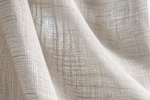 Close-up of textured sheer curtain fabric showing its natural weave and drape